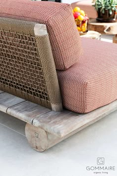 a couch sitting on top of a wooden bench next to potted plants and fruit