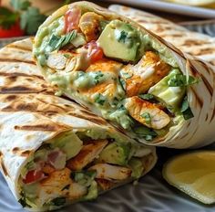 two burritos on a plate with avocado and chicken