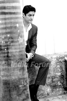 black and white photograph of a man sitting on a stone wall next to a palm tree