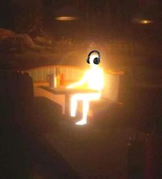 a person sitting at a table in the dark with a lit candle on it's side