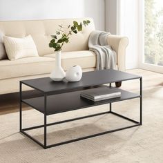 a coffee table with two vases on it in front of a couch and window