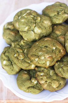 a white plate filled with green cookies on top of a wooden table