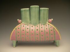 a green and pink vase sitting on top of a wooden stand with four candles in it