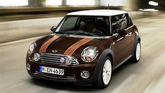 a brown and white mini car driving down the road