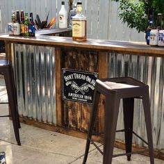 an outdoor bar with two stools next to it