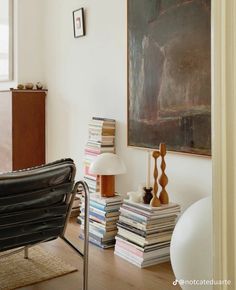 a living room filled with furniture and a painting on the wall next to a chair