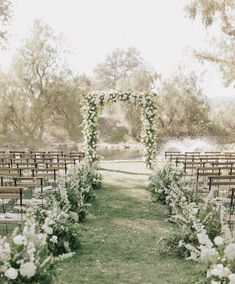 an outdoor ceremony setup with white flowers and greenery