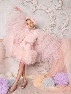 a woman in a pink dress sitting on top of a chair next to some fluffy balls