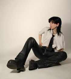 a woman sitting on the ground wearing black leather pants