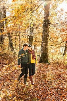 two people walking through the woods in autumn