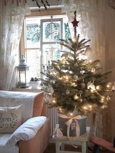 a small christmas tree sitting in the corner of a room next to a bed and window