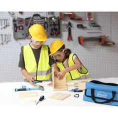 two children in safety vests and hard hats working on wood