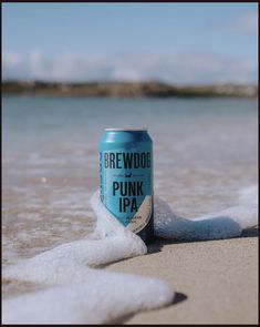 a can of beer sitting on top of a sandy beach