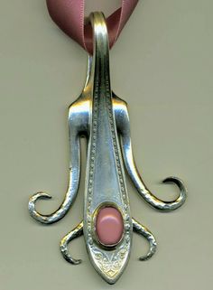 a metal object with a pink ribbon around it's neck on a white surface