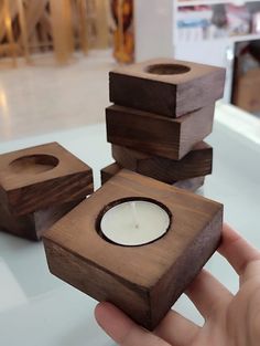 a person holding a candle in front of some wooden cubes with candles inside them