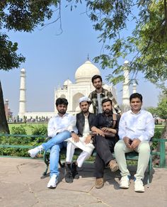 four men sitting on a bench in front of the taj muttra mosque