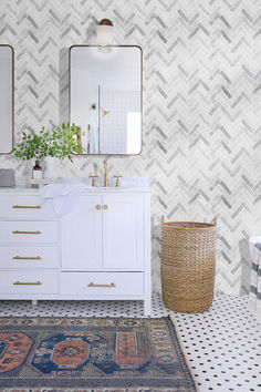 a bathroom with two mirrors, a sink and a rug on the floor in front of it