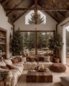 a living room filled with lots of furniture next to a large glass wall window covered in pine trees