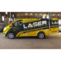 a yellow and black van is parked in a warehouse with other cars behind it that are also advertising laser