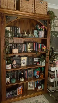 a wooden book shelf filled with lots of books next to a wall mounted clock and plant