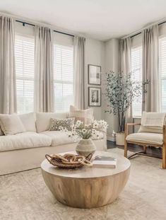 a living room with couches, chairs and a coffee table in front of two windows