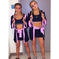 two girls in matching outfits with pink ribbons on their waists and one wearing black