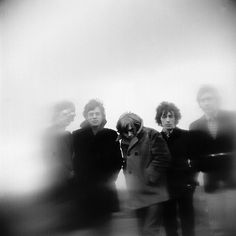 a group of people standing next to each other in front of a white wall with fog