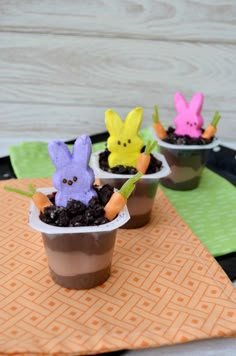 three small plastic cups filled with dirt and decorated like easter bunnies sitting on top of a table