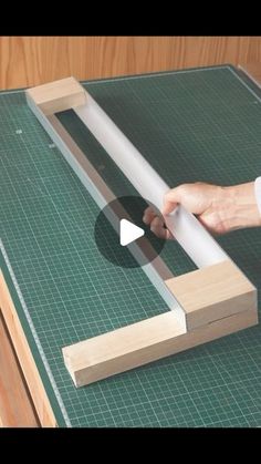 a person is cutting wood with a large piece of white paper on top of it