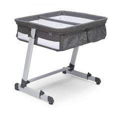 a grey and white baby crib sitting on top of a wooden stand with wheels