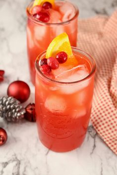 two glasses filled with orange and cranberry punch on top of a marble counter