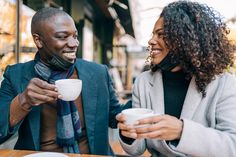 a man and woman sitting at a table drinking coffee