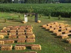 several rows of hay bales in the middle of a field with an outhouse