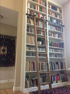 a ladder leaning up against a bookshelf in a room with rugs on the floor