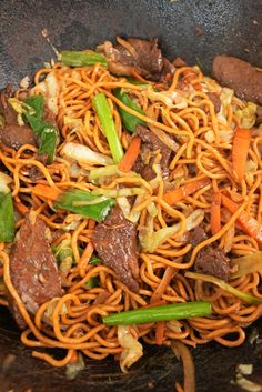 stir fried noodles with beef and vegetables in a wok