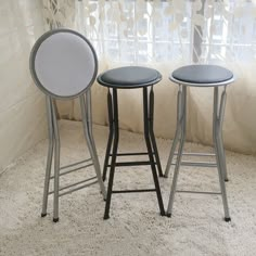 three stools sitting next to each other in front of a window with sheer curtains