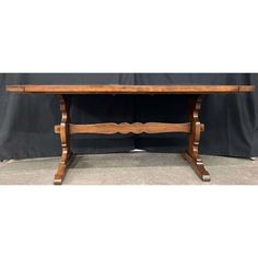 a wooden table sitting on top of a floor next to a black wall with a curtain behind it