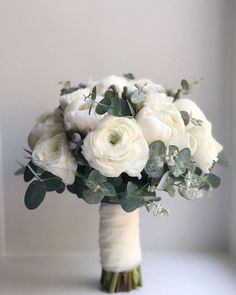 a bridal bouquet with white flowers and greenery