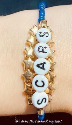 a close up of a person's hand wearing a bracelet with letters on it