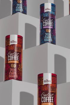 four cans of coffee sitting on top of each other in front of a white wall