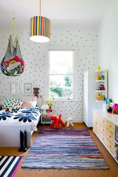 a child's bedroom with polka dot wallpaper and colorful rugs on the floor