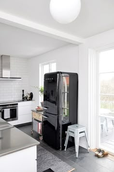 a black refrigerator sitting in the middle of a kitchen