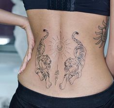 a woman's lower back with tattoos on her body and two tigers in the middle