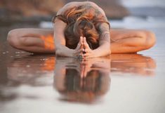 a woman doing yoga on the beach with her head in her hands and eyes closed