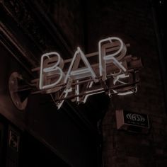 a neon sign that reads bar art on the side of a brick building at night