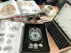 an open laptop computer sitting on top of a desk next to a book and cup