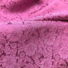 a pink fabric with flowers and leaves on the side, as if it were brocaded or embellished