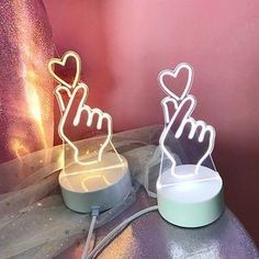 two light up hands on top of a table with a pink wall in the background