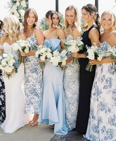 a group of women standing next to each other wearing dresses and holding bouquets in their hands