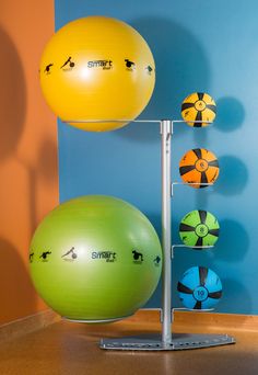 three exercise balls on a metal stand in front of a wall with blue and orange walls